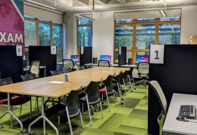 Large open-plan office with a long central table and green patterned carpet.