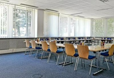 Spacious U-shaped meeting room with wooden chairs and large windows providing natural light.