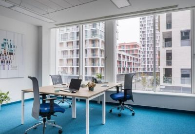 Private office space featuring two desks and large windows overlooking city buildings.