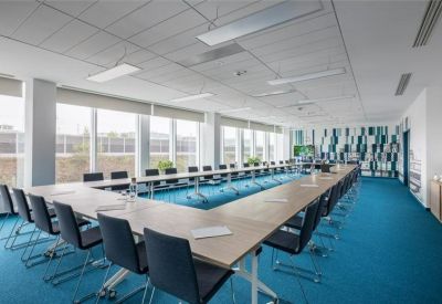Large U-shaped meeting room with dark chairs and blue carpet.
