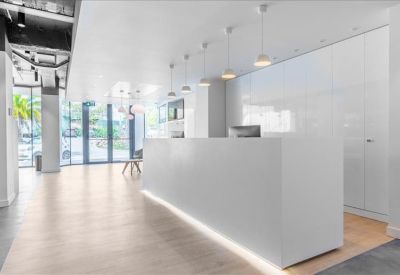 Sleek minimalist reception area featuring a long white desk and warm integrated floor lighting.