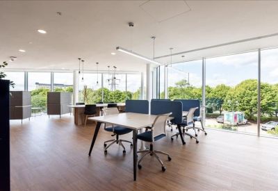 Bright coworking space with wooden floors, large windows, and central collaboration table.