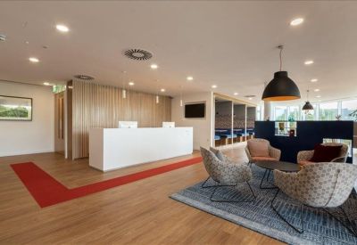 Reception area featuring a minimalist white desk, wooden floors, and a blue seating area.