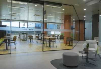 Café area with wooden tables and chairs separated by a glass partition from the main walkway.