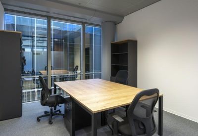 Two-person private office with wooden desk and views into a glass-walled meeting room.
