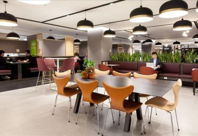 Large communal dining area with stylish wooden chairs and modern circular pendant lighting.