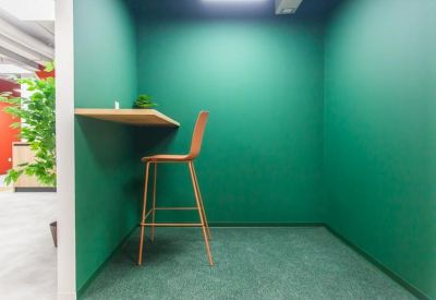 Private phone booth or single-person workspace with green walls and a high stool.
