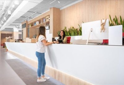 Professional reception desk with white finishes and indoor greenery.