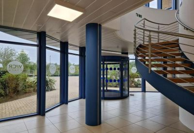 Lobby area featuring a blue structural pillar, revolving door, and modern staircase.