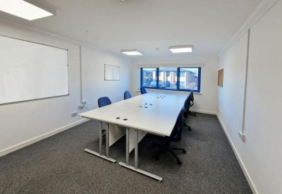 Bright conference room with a large white table and wall-mounted whiteboards.