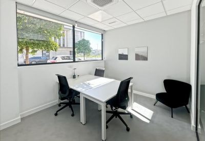 Private three-desk office with large windows and a black accent armchair.