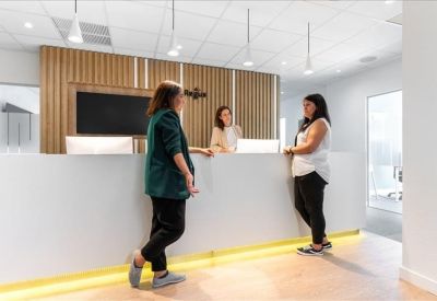 Modern reception desk with wooden slat feature wall and three staff members.