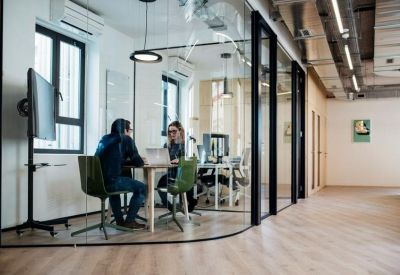 Meeting room with glass walls, a round table, and industrial-style ceiling elements.