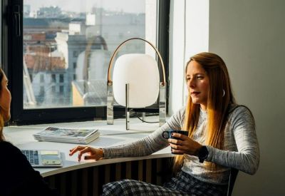Close-up of a person having a coffee in a bright workspace with a large modern lamp.