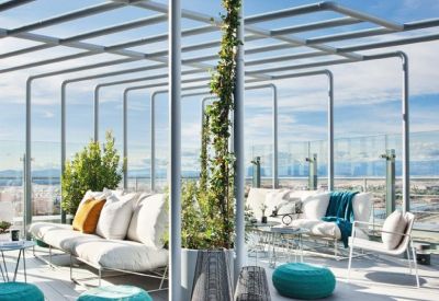 Rooftop terrace with modern white sofas, blue ottomans, and a metal pergola structure.