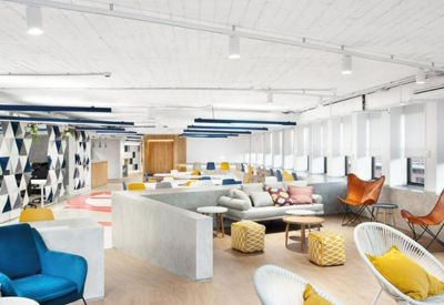 Eclectic communal lounge featuring colorful seating, yellow cushions, and a mid-century modern aesthetic.