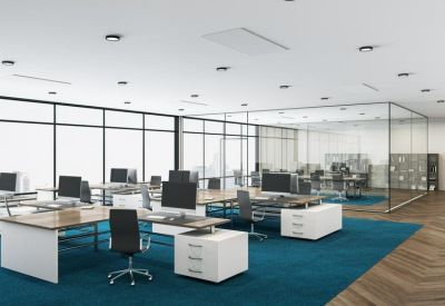 Spacious open-plan workspace with teal carpeting and glass-walled meeting rooms.