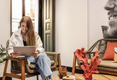 Sunny lounge area at Calle de las Huertas, 11, with a woman working on a tablet near vibrant artwork.