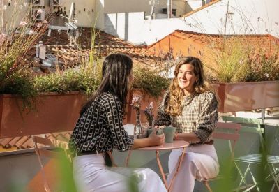 Rooftop terrace with pink tables and chairs overlooking classic city architecture.