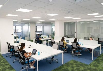 Large open-plan coworking space with several people working at white desks.