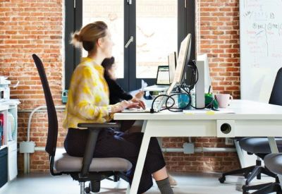 Industrial style office with exposed brick walls and a person working at a white desk.