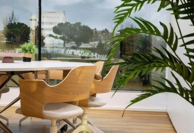Meeting area with wooden chairs and a white table overlooking a leafy outdoor view.