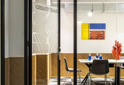 Glass-walled meeting room with geometric patterned flooring and framed artwork.