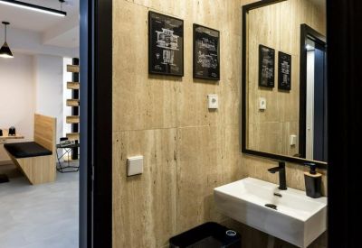 Modern bathroom with wood-paneled walls, a white vessel sink, and black fixtures.