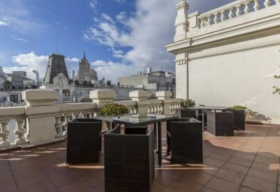 Spacious rooftop terrace with modern black outdoor furniture and views of the surrounding city skyline.