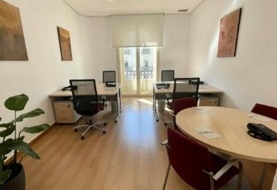 Private office suite with two workstations, a small round meeting table, and framed wall art.