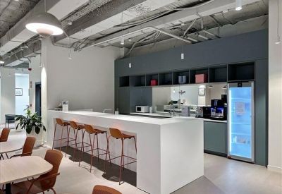 Modern office kitchen and breakout area with a long white breakfast bar and bar stools.