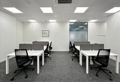Open-plan workspace with white desks and black ergonomic chairs.