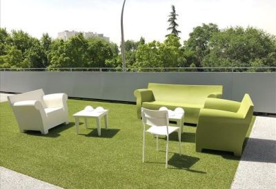 Outdoor terrace with artificial grass and green and white lounge furniture.