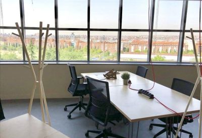 Meeting area with a white table, black chairs, and a view of the city through large windows.