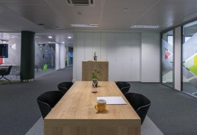 Large wooden meeting table in a minimalist grey-toned conference room.