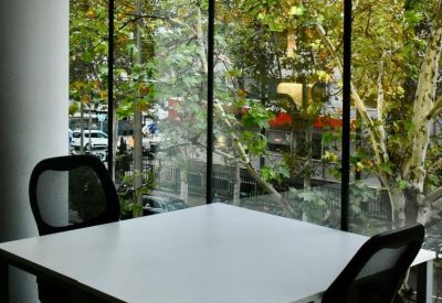 Two-person desk layout beside large floor-to-ceiling windows with tree views.