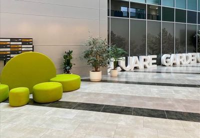 Contemporary office reception area with bright green stools and sleek marble flooring.