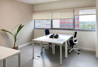 Three-person private office suite with white desks and large windows.