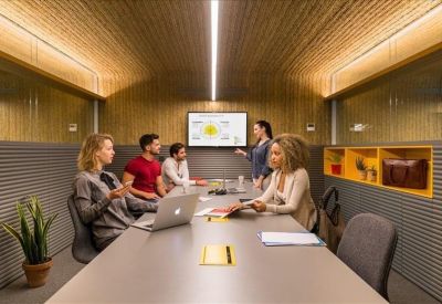 Modern meeting room with wood-paneled walls, a large screen, and natural lighting.