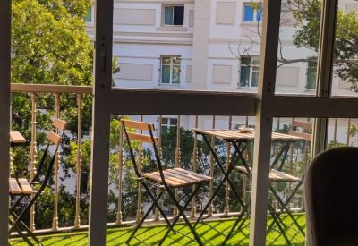 Private balcony with green artificial turf and small wooden bistro tables.