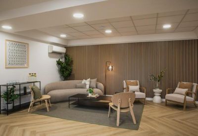 Modern lounge area with a curved beige sofa, armchairs, and wood-slat feature wall.