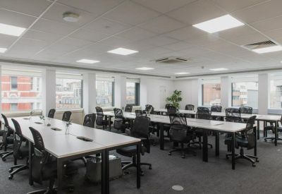 Spacious open-plan workspace with multiple rows of desks and ergonomic black chairs.