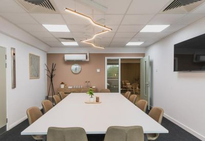 Bright conference room with a large white table and a wall-mounted television.