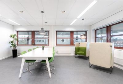 Modern breakout or meeting space with green privacy booths and a large white table.
