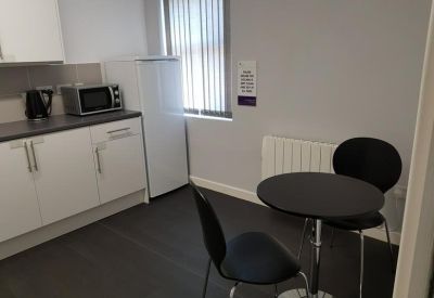 Modern communal kitchen and dining area with white cabinetry and a round bistro table.