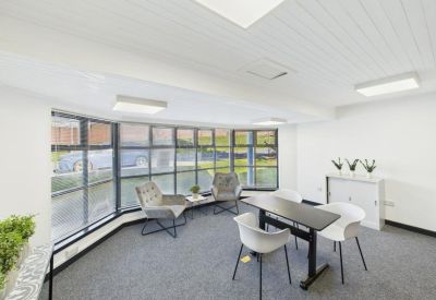 Spacious meeting area with a curved window wall, modern chairs, and a black conference table.
