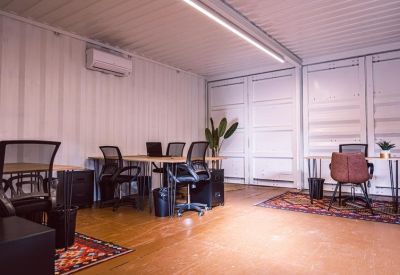 Industrial-style workspace with multiple desks and ergonomic chairs.