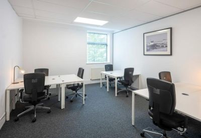 Bright four-person office suite with white desks and black mesh chairs.