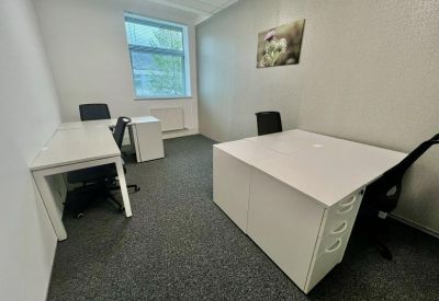 Small private office with L-shaped desks and a decorative wall picture.