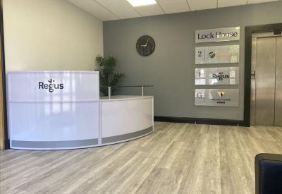 Curved white reception desk with branded logo and directories on a grey feature wall.